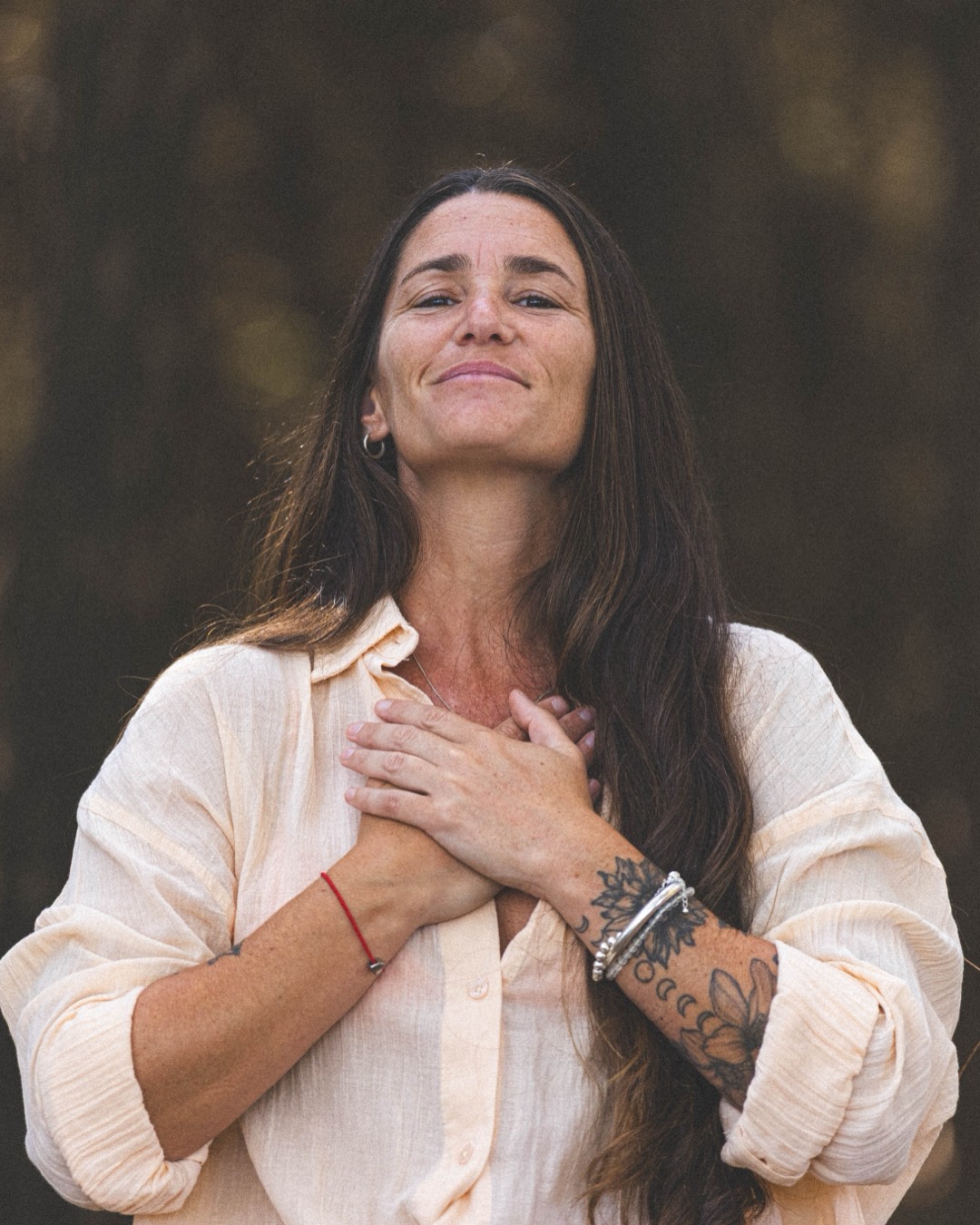 María Laura en el bosque, las manos en el pecho, en gratitud